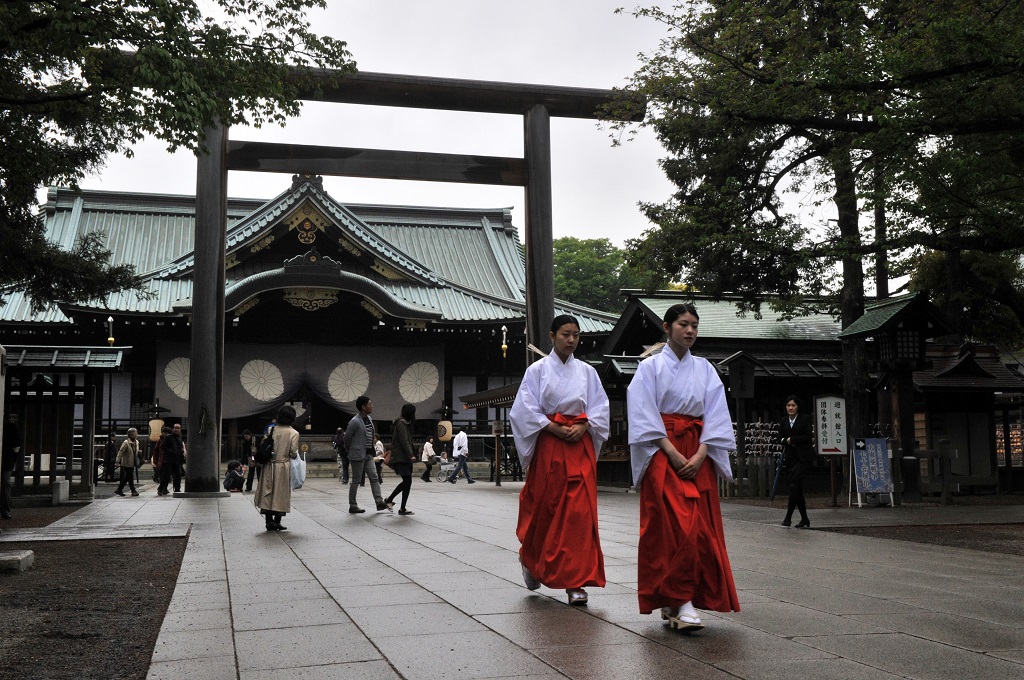 Dua perempuan Shinto Maiden berjalan di depan Kuil Yasukuni di Chiyoda, Tokyo, Jepang -- YOSHIKAZU TSUNO / AFP