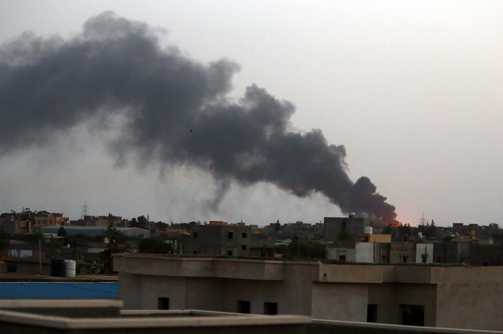 Asap membumbung dari sebuah depot minyak dekat bandara internasional Tripoli, Libya, dalam bentrokan antar militan Islam  -- MAHMUD TURKIA / AFP