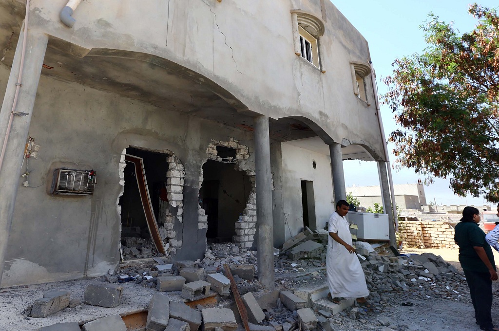 Warga berdiri di dekat sebuah rumah yang hancur dalam pertempuran faksi bersenjata di Tripoli, Libya -- MAHMUD TURKIA / AFP