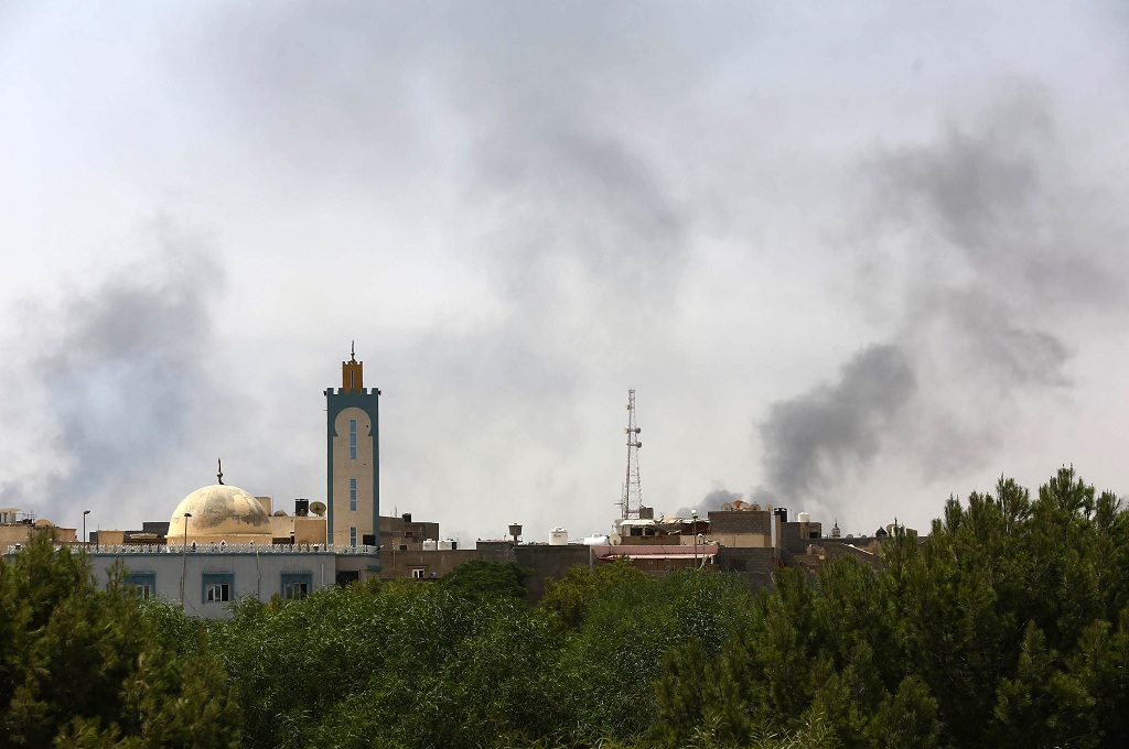 Asap membumbung dari dekat bandara internasional Tripoli, Libya, dalam bentrokan antar militan Islam  -- MAHMUD TURKIA / AFP