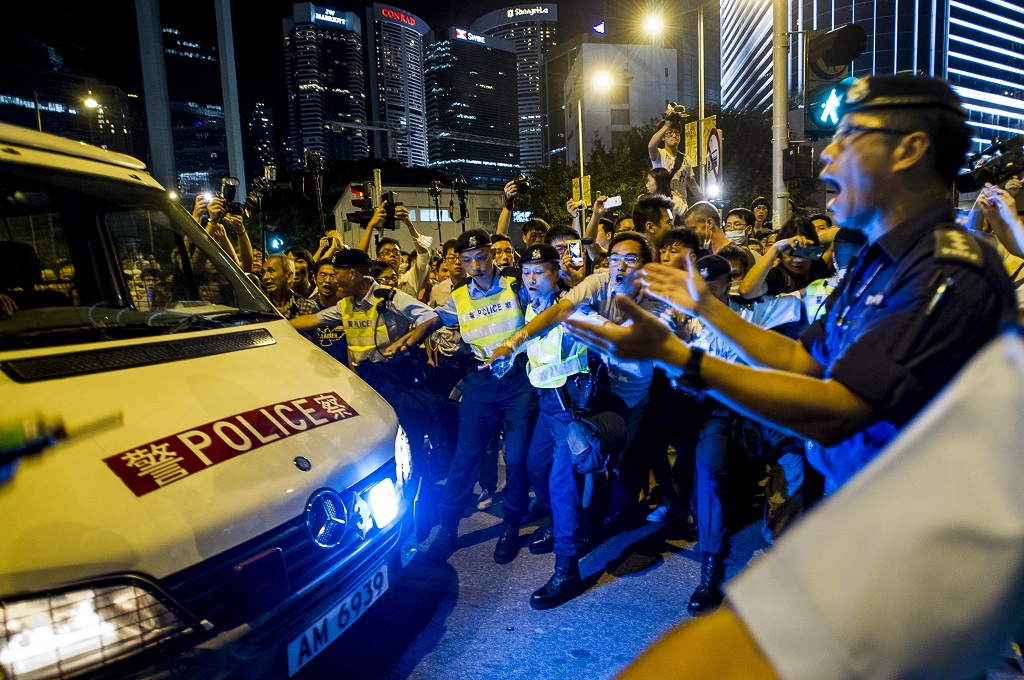 Polisi Hong Kong membuat pagar betis dalam membuka jalan untuk sebuah kendaraan di tengah unjuk rasa warga di kompleks pemerintahan Hong Kong - AFP/Xaume Olleros
