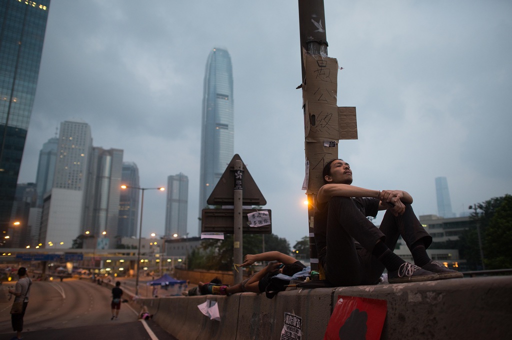 Pendemo pro demokrasi Hong Kong duduk di pinggir jalanan yang sepi dari kendaraan - AFP/ED Jones