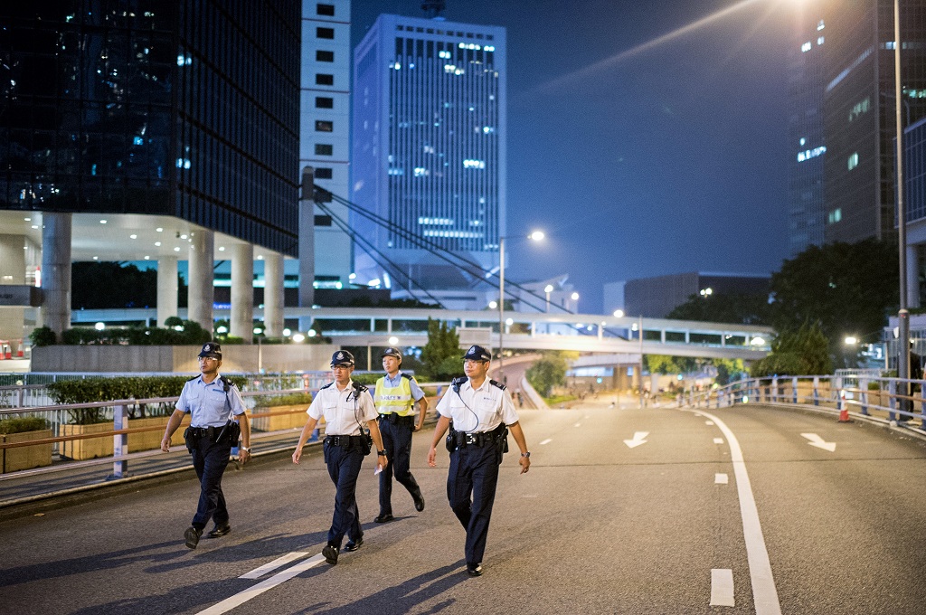 Polisi berpatroli di jalan raya yang kosong melompong di Hong Kong - AFP/Alex Ogle