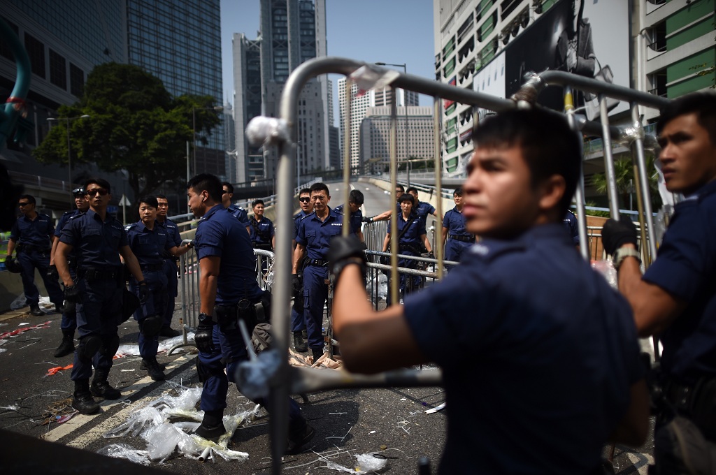 Polisi mengangkut barikade besi yang dipasang demonstran di distrik Admiralty, Hong Kong - AFP/ED Jones