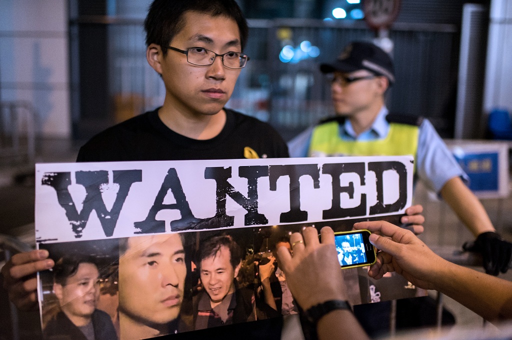 Poster bertuliskan Wanted memperlihatkan foto sejumlah polisi yang memukuli demonstran Hong Kong pada Rabu (15/10/2014) - AFP/Alex Ogle