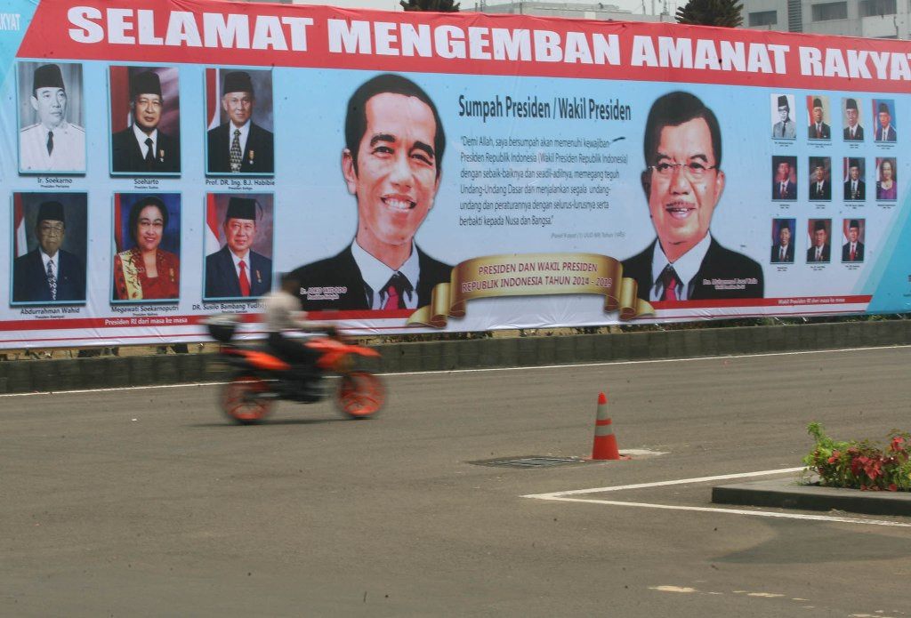 Pengunjung melintas di depan baliho pasangan Presiden Joko Widodo dan Wakil presiden Jusuf Kalla di Halaman Kompleks Parlemen, Senayan, Jakarta, Rabu (16/10/2014). MI/Mohamad Irfan
