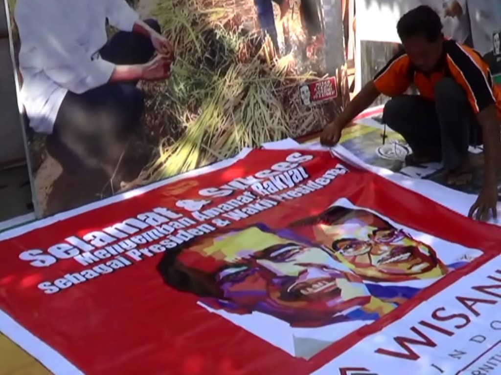 Seorang pekerja menggelar spanduk ucapan selamat yang telah dipesan berbagai kalangan di Solo, Jateng, Jumat (17/10/2014), untuk menyambut pelantikan Joko Widodo dan Jusuf Kalla sebagai Presiden dan Wapres RI. MTVN/Eka Hari Wibawa