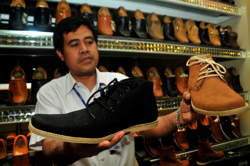 Seorang karyawan menunjukkan dua model sepatu berwarna coklat dan hitam di Toko Grutty Shoes, Cibaduyut, Bandung, Kamis (2/10/2014). 