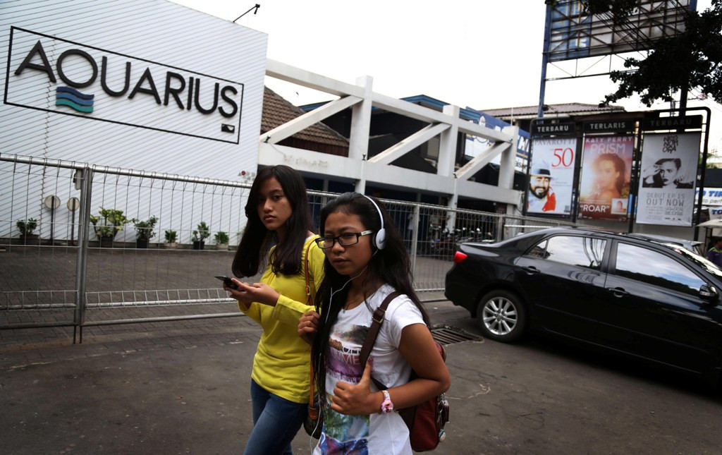 MATINYA IKON MUSIK INDONESIA: Remaja mengenakan headset melintas didepan toko Aquarius Mahakam yang sudah Tutup. Foto: Dok MI)