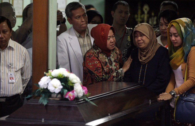 Ibu korban pesawat AirAsia QZ8501 (dua kanan) menangis di depan peti jenazah didampingi Wali Kota Surabaya Tri Rismaharini (tiga kanan) saat proses penyerahan Jenazah Hayati Lutfiah Hamdi di RS Bhayangkara Polda Jatim, Surabaya, Jawa Timur, Kamis (1/1). M