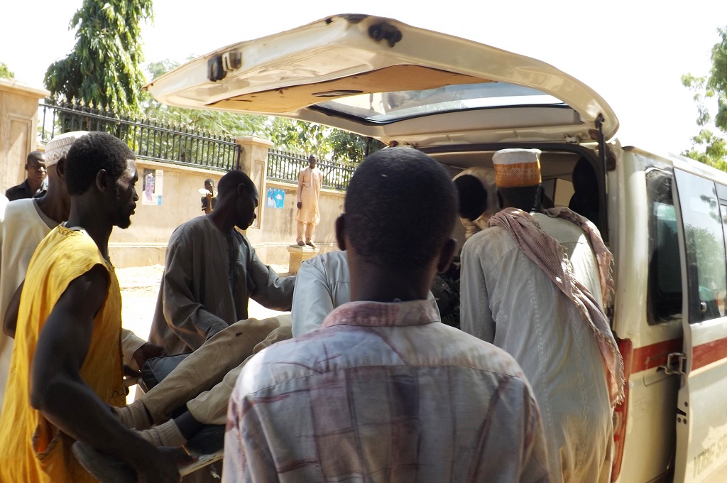 Warga menggotong korban ledakan bom bunuh diri di luar rumah seorang politisi di Potiskum, Nigeria - AFP / AMINU ABUBAKAR
