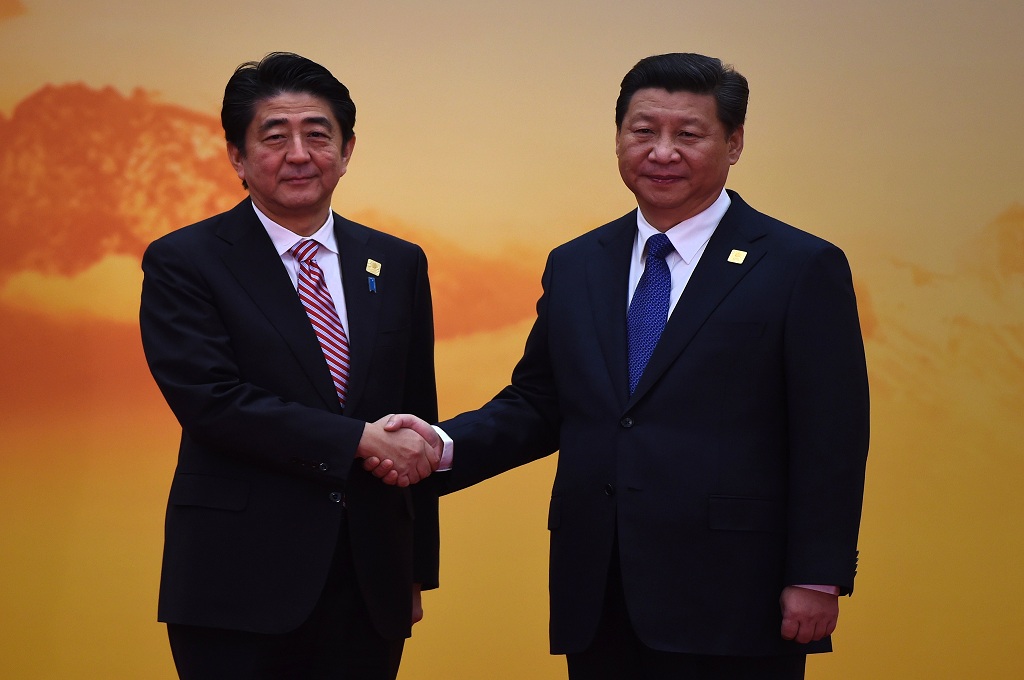 Perdana Menteri Jepang Shinzo Abe (kiri) bersalaman dengan Presiden Tiongkok Xi Jinping dalam APEC 2014 di Beijing - AFP / GREG BAKER