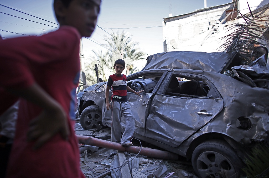 Anak-anak bermain di sekitar mobil milik kelompok Hamas yang hancur di Jalur Gaza - AFP / THOMAS COEX