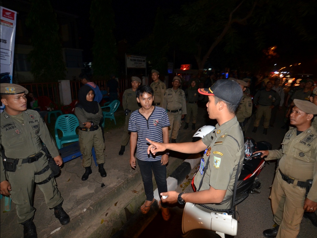 Petugas Satpol PP Kota Jambi memberikan pengarahan kepada pengunjung dan pemilik kafe saat razia penyakit masyarakat (pekat) di salah satu kafe dengan penerangan yang minim di Kota Baru, Jambi, Kamis (12/2) malam. (Foto: ANTARA FOTO/Wahdi Septiawan)