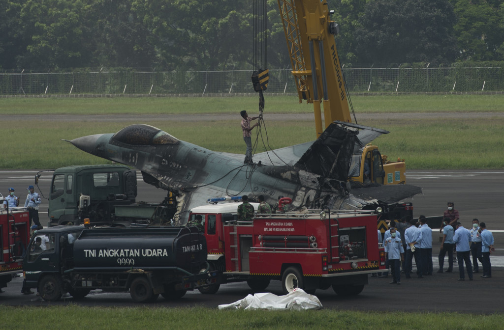 Petugas mengaitkan tali di pesawat tempur F-16 yang terbakar di ujung landasan pacu Pangkalan Udara Halim Perdanakusuma, Jakarta Timur, Kamis (16/4). Antara Foto/Rosa Pangabean