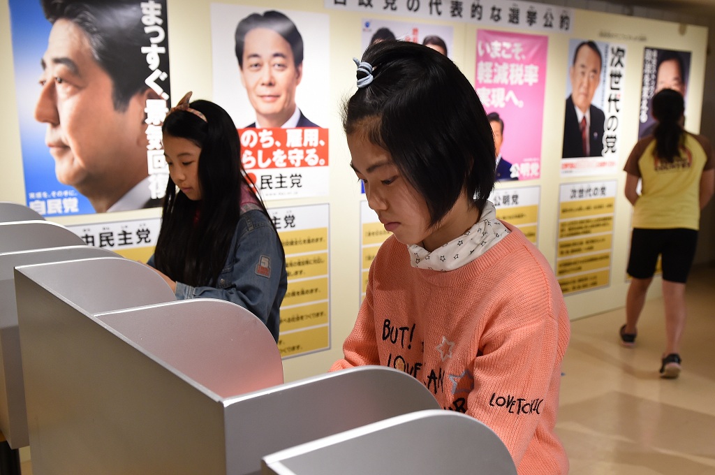 Dua gadis usia sekolah berlatih mengikuti pemilu di Jepang pada 2014. Jepang menurunkan usia pemilih pemula dari 20 menjadi 18, Rabu (17/6/2015) AFP / TORU YAMANAKA