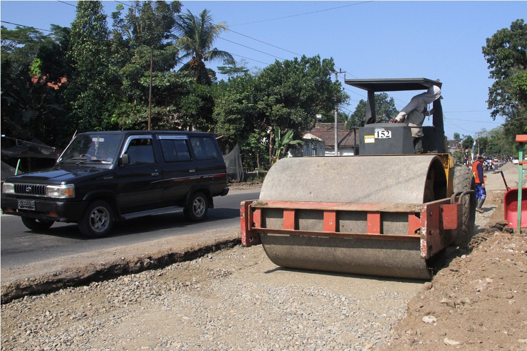 Pekerja melakukan pengerasan jalan pada proyek pelebaran arteri jalan nasional di Trenggalek, Jawa Timur, Kamis (2/7). Foto: Antara/Destyan Sujarwoko
