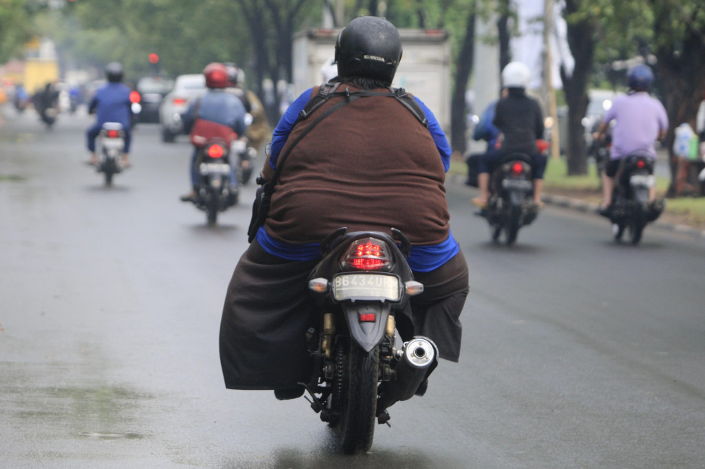 Seorang pengendara sepeda motor dengan tubuh kegemukan atau obesitas melintas di kawasan Pluit, Jakarta Utara. (foto: MI/Rommy Pujianto)