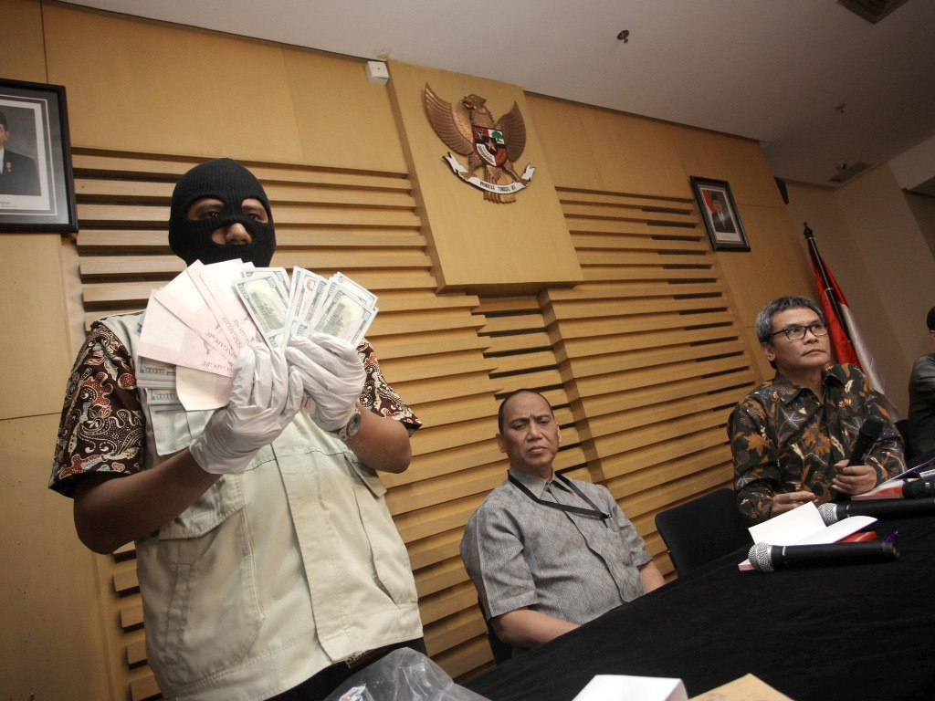 Petugas KPK menunjukkan uang dolar AS dan dolar Singapura yang merupakan barang bukti hasil OTT (Operasi Tangkap Tangan) disaksikan Plt Pimpinan KPK Johan Budi (kanan) dan Indrianto Seno Aji (tengah) di Gedung KPK, Jakarta, Jumat (10/7). (Foto: ANTARA FOT