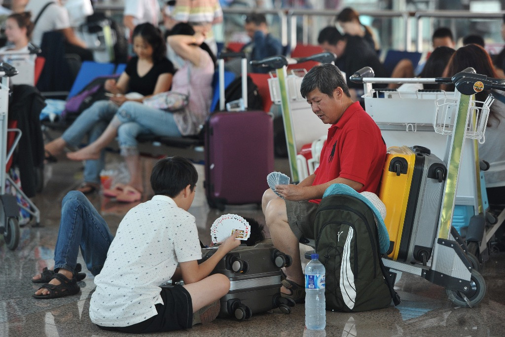 Sejumlah warga negara asing bermain kartu saat menunggu kepastian penerbangannya di Terminal Internasional Bandara Ngurah Rai, Denpasar, Sabtu (8/8). Foto: Antara/Nyoman Budhiana