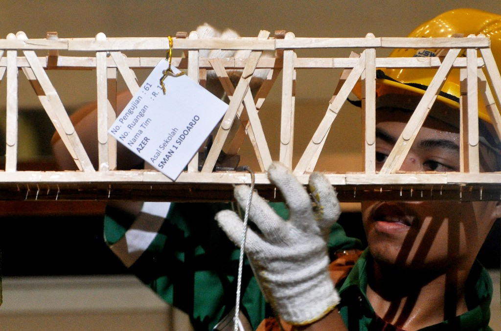 Mahasiswa Institut Teknologi Sepuluh Nopember (ITS) menguji kekuatan jembatan yang terbuat dari stik es krim saat penjurian Bridge Construction Competition di Surabaya, Jawa Timur (26/4). Foto: Antara/Herman Dewantoro