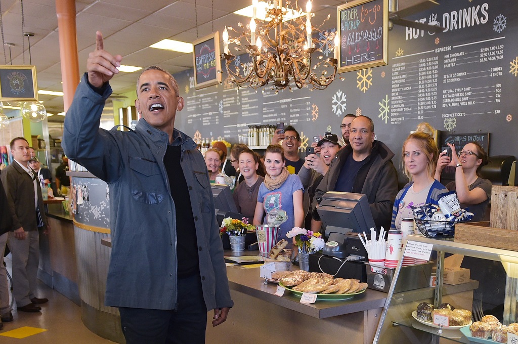 Presiden AS Barack Obama menawarkan kue kepada para staf Gedung Putih dan juga awak media di sebuah kafe di Anchorage, Alaska, Selasa (1/9/2015). (Foto: AFP / MANDEL NGAN)
