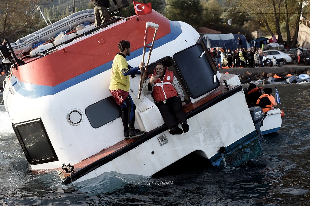Petugas menyelamatkan imigran dari sebuah kapal yang mulai tenggelam di lepas pantai Pulau Lesbos, Yunani, 30 Oktober 2015. (Foto: AFP/ARIS MESSINIS)