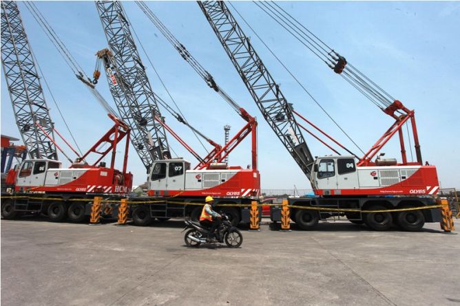 Pekerja pelabuhan melintas di depan mobil crane.ANTARA FOTO/Muhammad Adimaja.