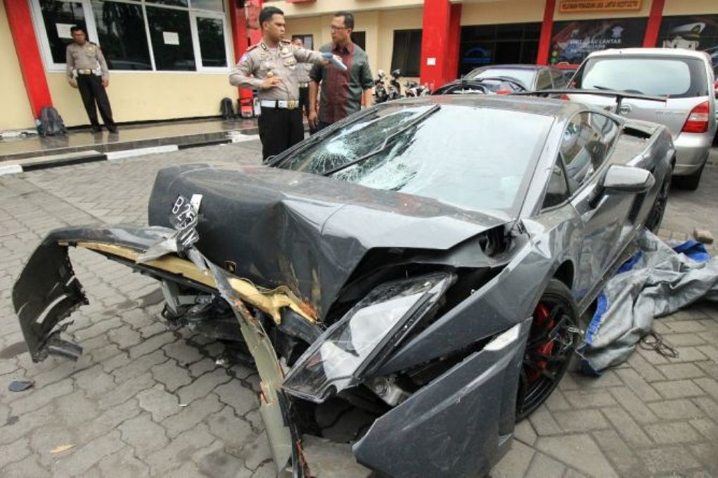 Polisi memeriksa barang bukti mobil Lamborghini yang rusak akibat kecelakaan di Surabaya, Jawa Timur, Minggu (29/11). (Ant/Didik Suhartono)