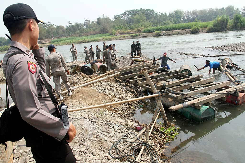 Polisi berjaga jaga saat petugas satpol PP merazia penambangan pasir liar/ilegal menggunakan mesin mekanik di bantaran Sungai Brantas, Tulungagung, Jawa Timur, Kamis (22/10).  (Foto: ANTARA/ Destian Sujarwoko)
