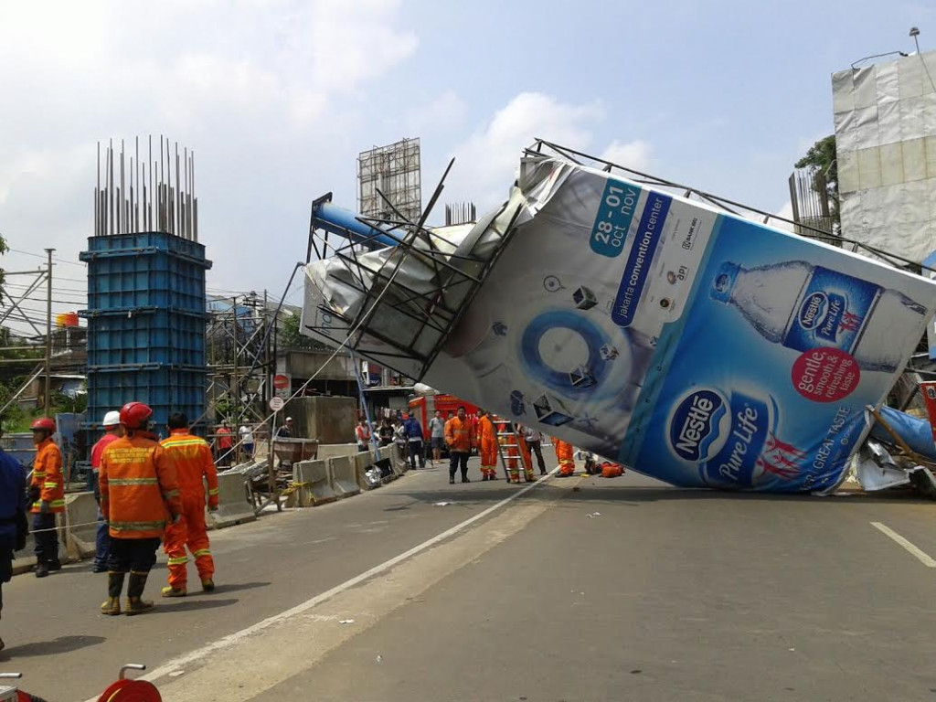 Petugas Damkar tengah merobohkan papan raklame yang roboh,--Foto: MTVN/Eko Nordiansyah