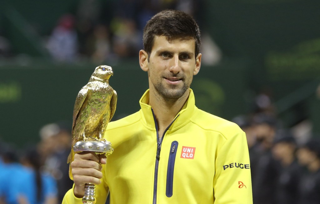 Petenis Serbia Novak Djokovic berpose dengan trofi turnamen Qatar Open 2016. (AFP PHOTO / KARIM JAAFAR)