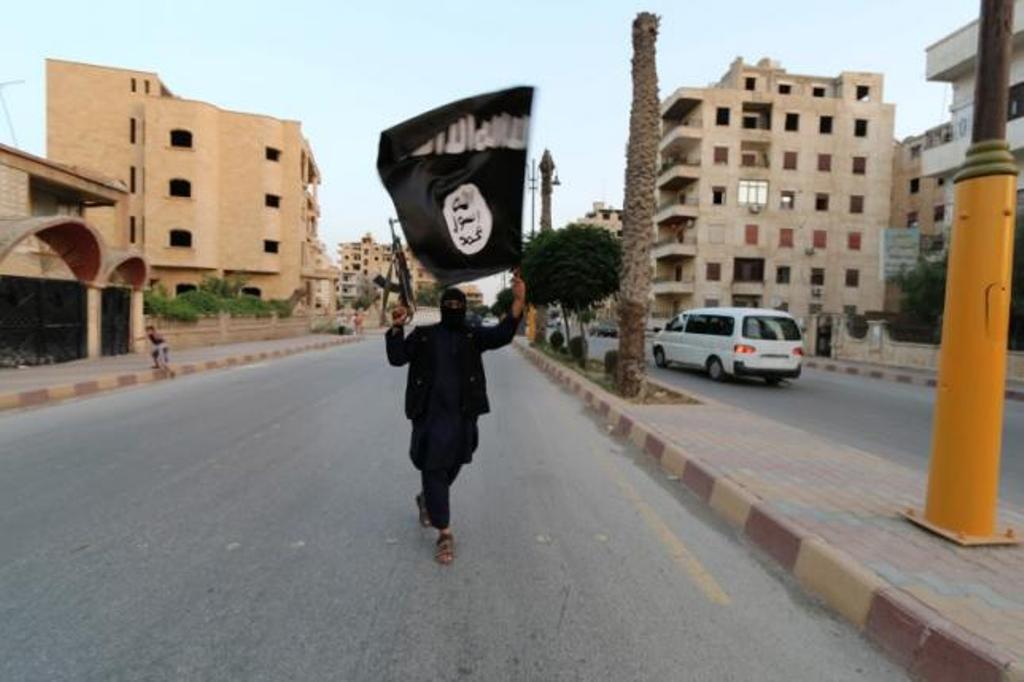 Seorang anggota ISIS mengibarkan bendera ISIS di Raqqa (Foto: Reuters)