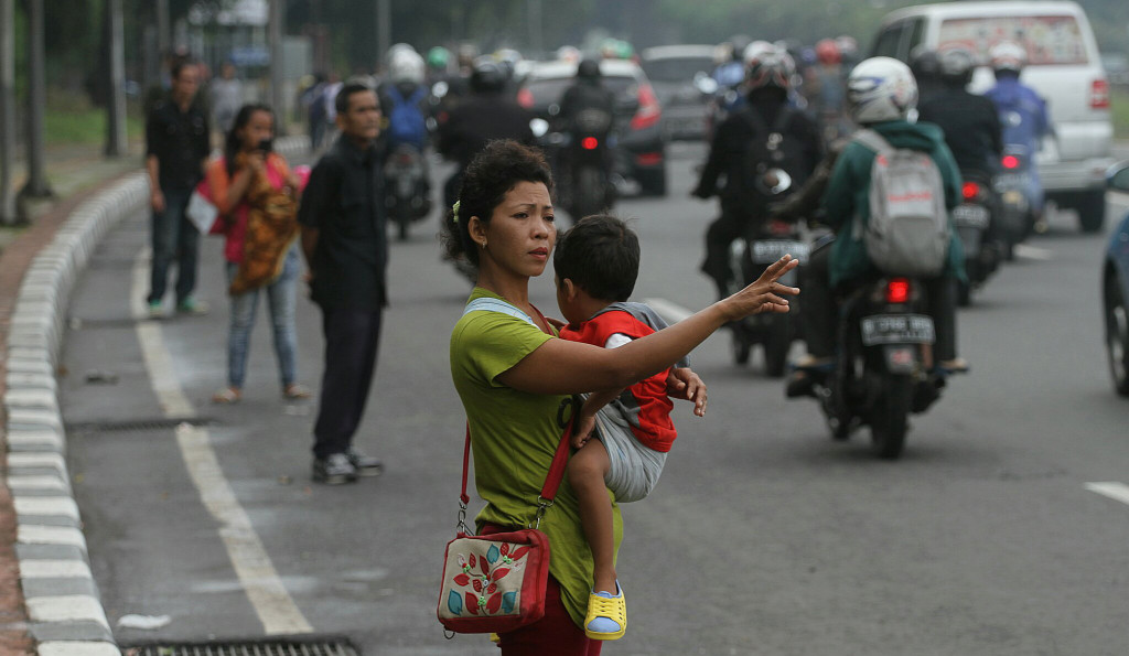 Joki 3 in 1 sambil menggendong anak menawarkan jasa tumpangan kepada pengendara mobil di Jalan Gatot Subroto, Jakarta, Selasa 29 Maret 2016. Foto: MI/Arya Manggala