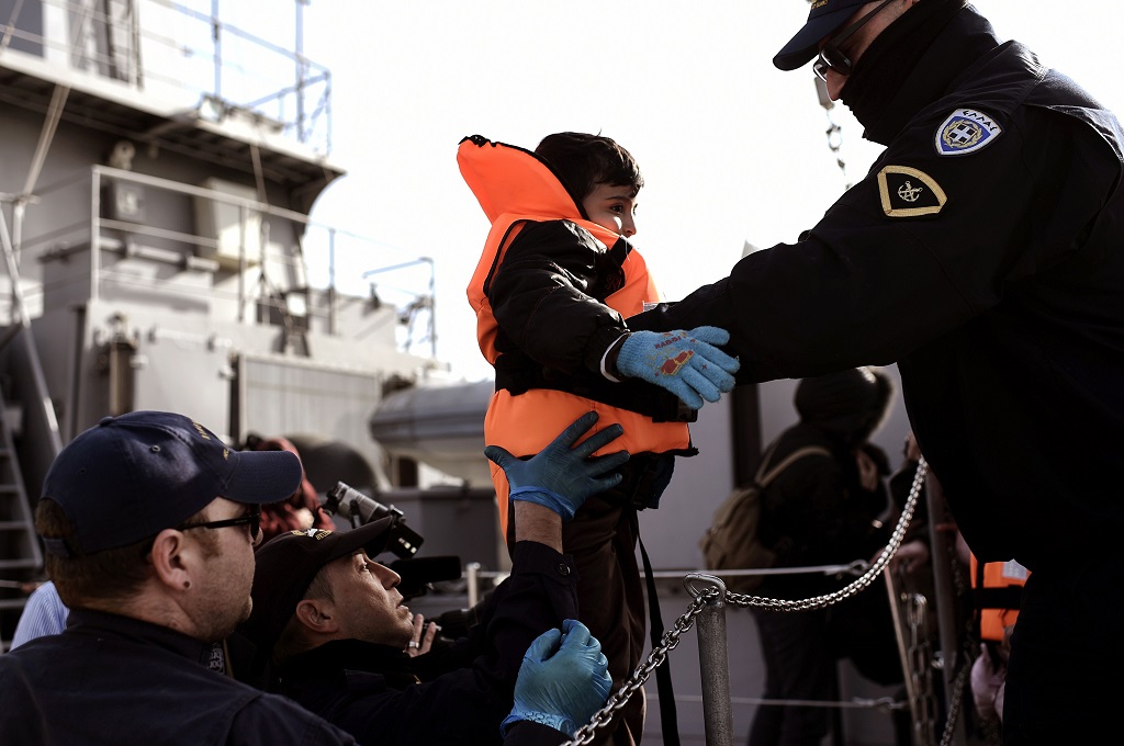 Seorang petugas mengangkat pengungsi anak-anak usai turun dari kapal di Mytilene, pulau Lesbos, Yunani, 4 April 2016. (Foto: AFP/ARIS MESSINIS)