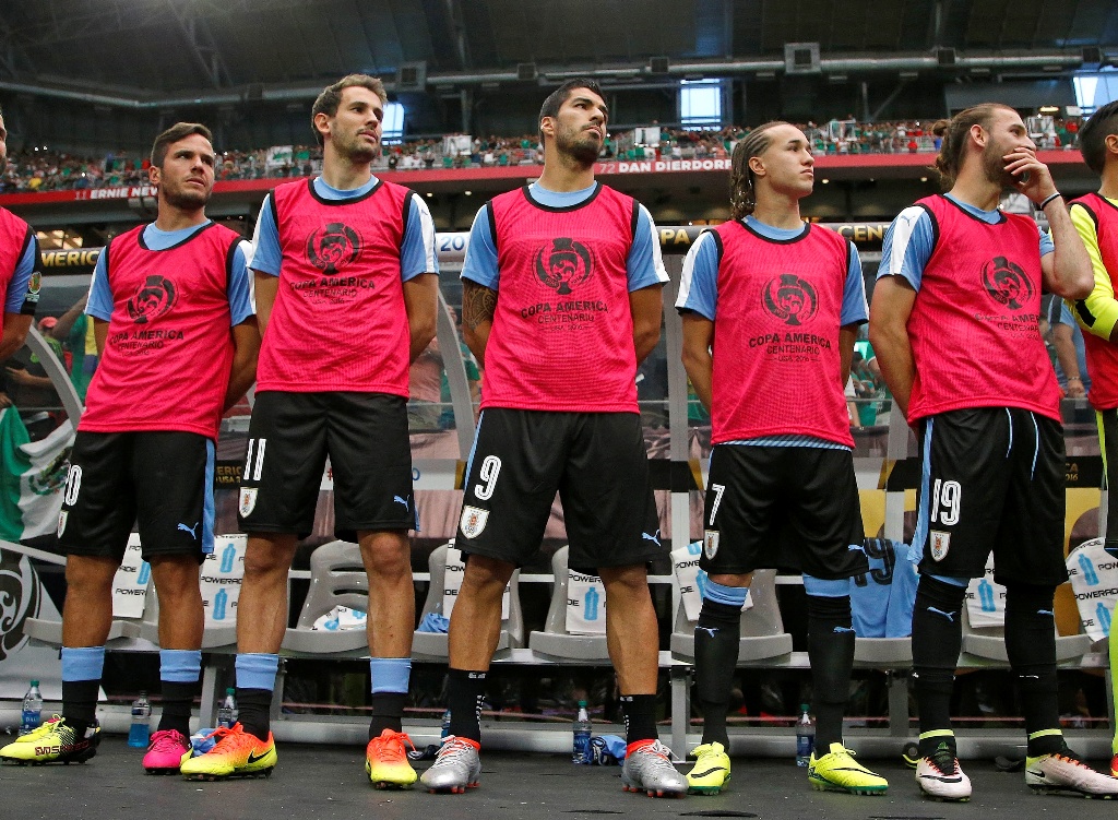 Para pemain cadangan Uruguay, termasuk Luis Suarez (tengah) terlihat saat mendengarkan lagu kebangsaan yang salah diputar (Foto: AP)