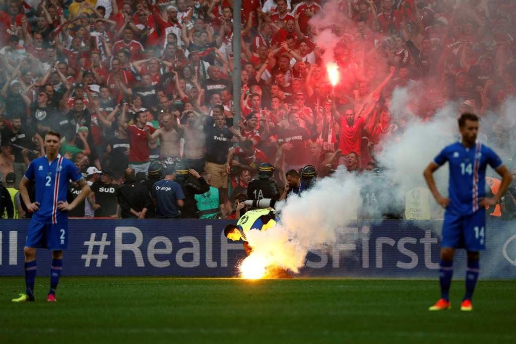Petugas keamanan berusaha menyingkirkan flare yang dilempar suporter Hungaria. (AFP PHOTO / ODD ANDERSEN)