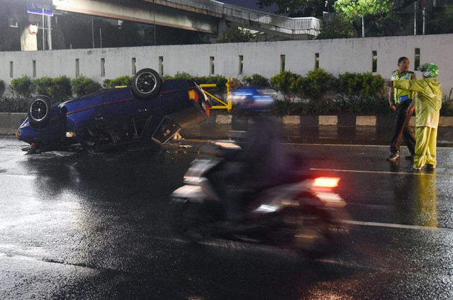 Anggota kepolisian berjaga di lokasi kecelakaan mobil yang terbalik di Jalan Gatot Subroto, Jakarta, Selasa (5/7) -- ANT/Akbar Nugroho Gumay