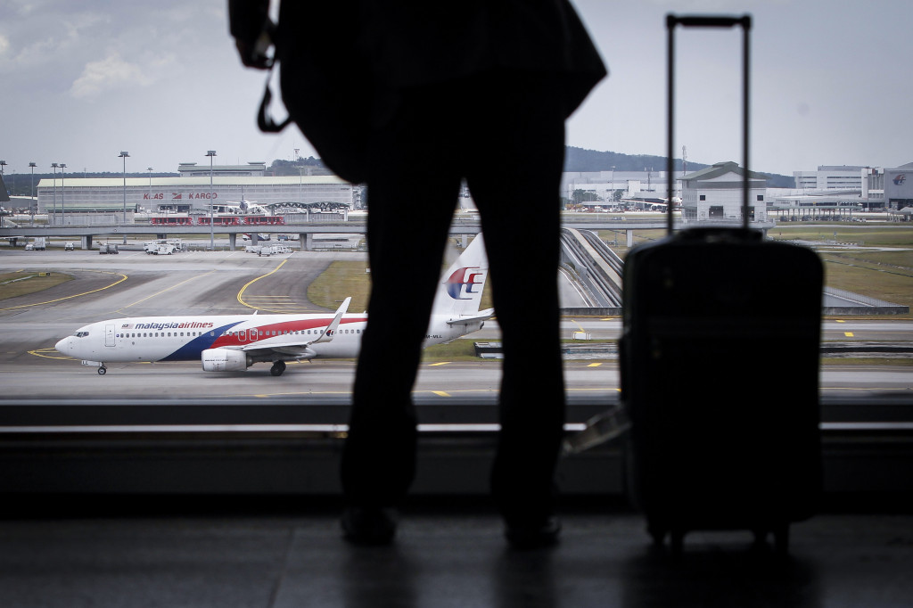 A traveller is silhouetted against a Malaysia Airlines plane at the Kuala Lumpur International Airport in Sepang, Malaysia. (AP Photo/Joshua Paul)