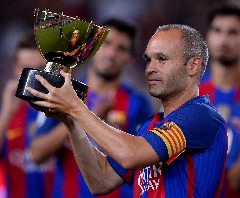 Kapten Barcelona Andres Iniesta mengangkat trofi Joan Gamper. (JOSEP LAGO / AFP)