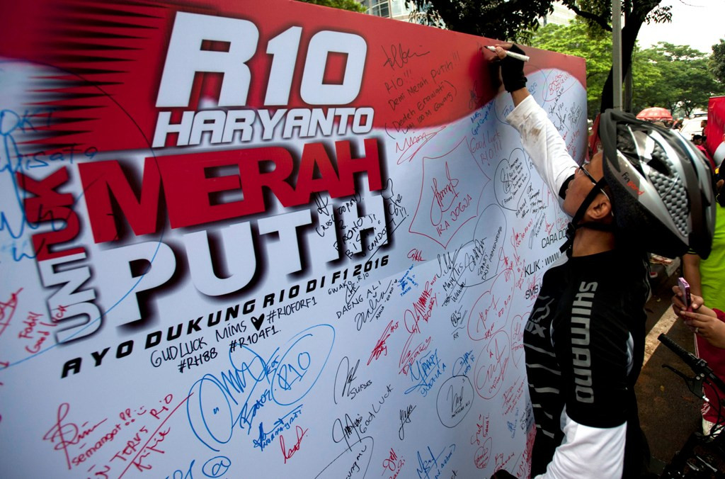 Salah satu warga tengah menuliskan pesan dukungannya kepada Rio Haryanto yang berlaga di Formula 1 (Foto: ANTARA FOTO/Wahyu Putro A)