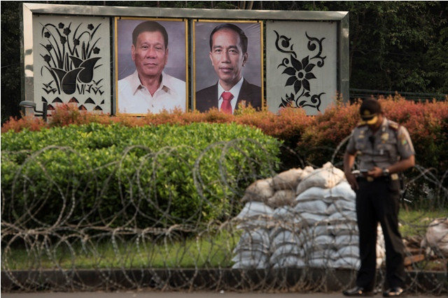  Polisi berdiri di dekat foto Presiden Joko Widodo dan Presiden Filipina Rodrigo Duterte. Foto: Antara/Sigid Kurniawan