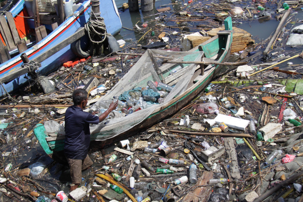 Seorang pemulung menggunakan perahu mengumpulkan sampah plastik di Daerah Aliran Sungai Krueng Aceh, Banda Aceh. (ANTARA FOTO/Ampelsa)