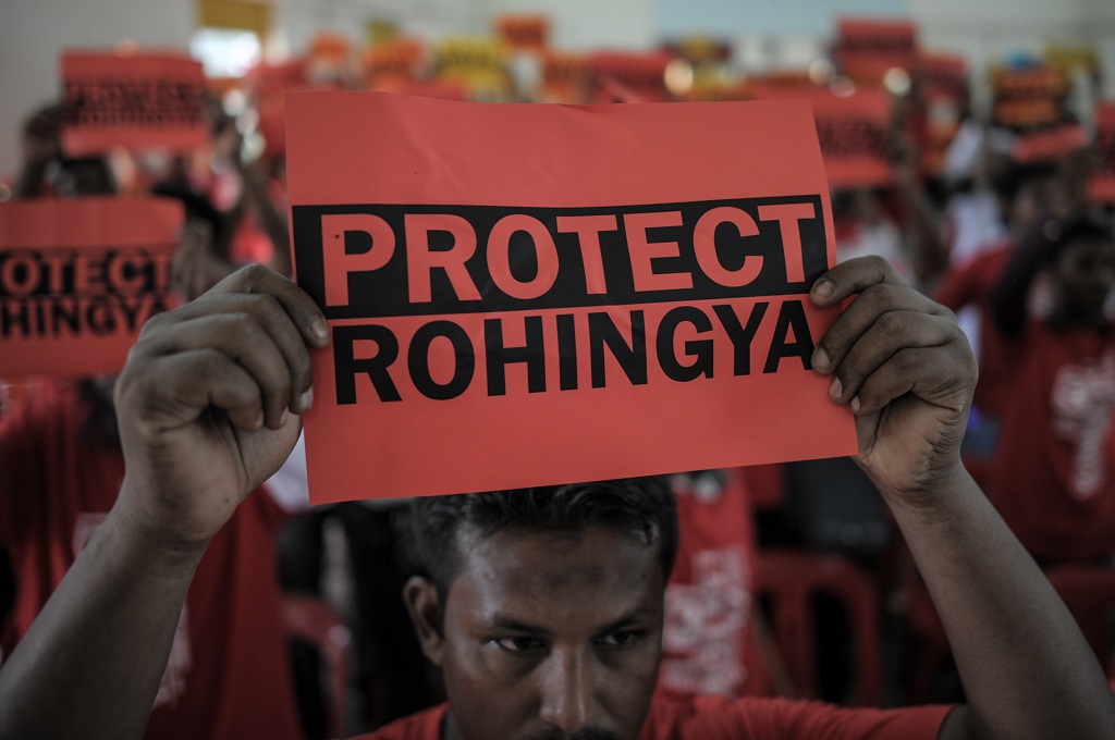 Pengungsi Rohingya memegang spanduk bertuliskan Lindungi Rohingya. (Foto: AFP)