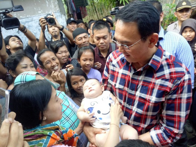 Petahana Gubernur DKI Jakarta Basuki Tjahaja Purnama menggendong beberapa bayi yang disodorkan warga di kawasan Asem 2, Cipete Selatan, Cilandak, Jaksel. Foto: MTVN/Arga Sumantri