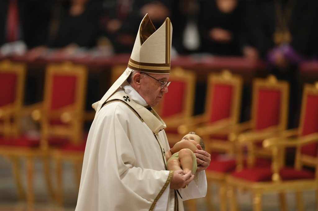 Paus Fransiskus membawa patung bayi Yesus dalam misa malam Natal di Basilika Santo Petrus, Vatikan, 24 Desember 2016. (Foto: AFP/ANDREAS SOLARO)