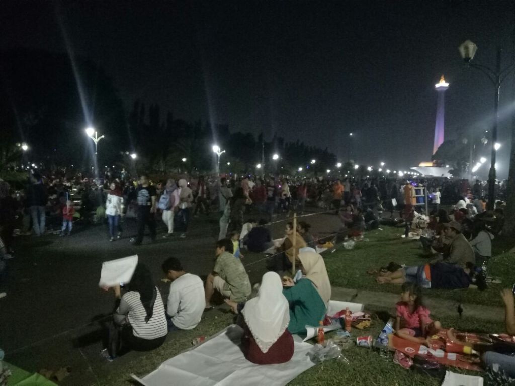 Warga duduk di atas rumput Kawasan Monas. (Foto: MTVN/Arga Sumantri).