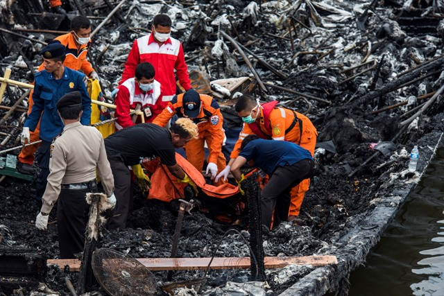 Petugas gabungan mengangkat kantong jenazah korban kebakaran kapal motor Zahro Express di Pelabuhan Kali Adem, Muara Angke, Jakarta, Minggu (1/1). Foto: M Agung Rajasa/Antara.