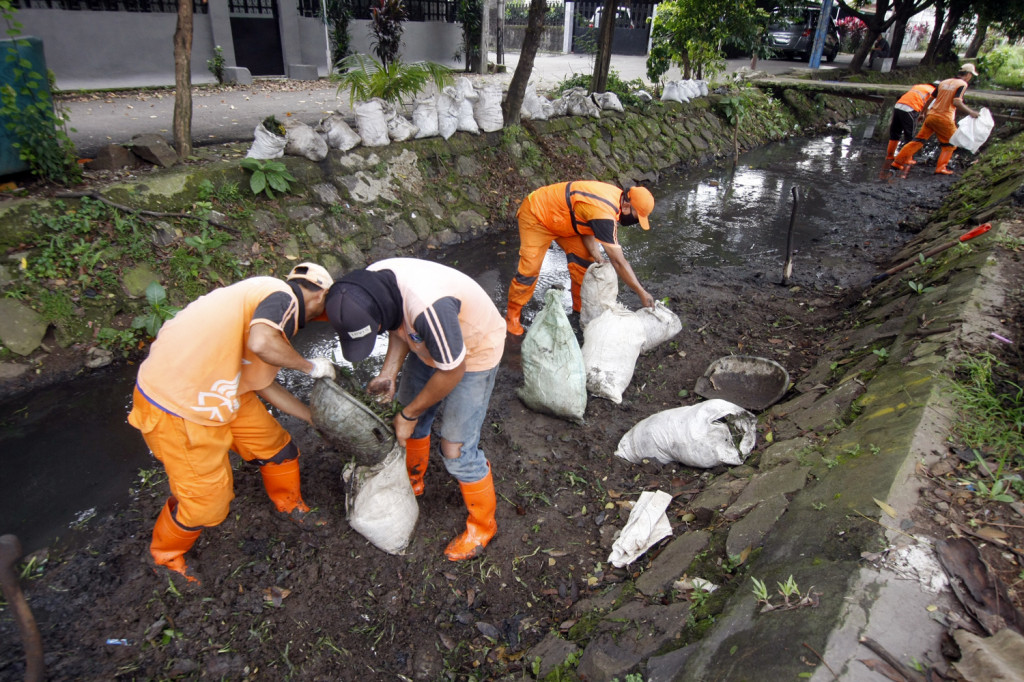 Petugas Penanganan Prasarana dan Sarana Umum (PPSU) atau pasukan oranye membersihkan saluran air dari lumpur dan sampah di Jalan Raya Karang Tengah, Lebak Bulus, Jakarta. Foto:MI/BARY FATHAHILAH