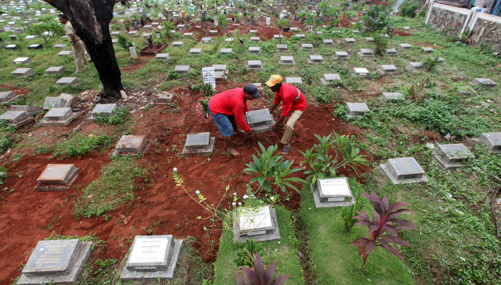 Petugas pemakaman memindahkan batu nisan dari makam fiktif di tempat pemakaman umum (TPU) Kawi-kawi, Jakarta Pusat, Senin (25/7/2016). Foto: MI/Panca Syurkani